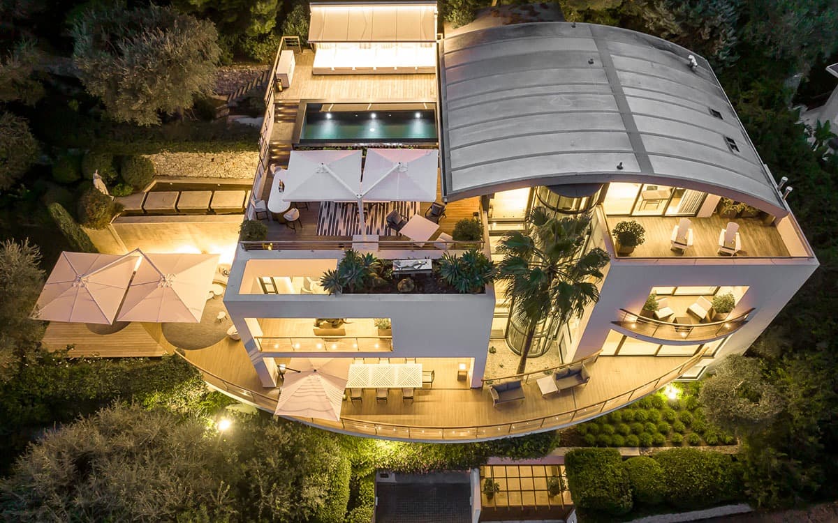 Aerial night view of Villa Céleste, curved roof, terraces and rooftop pool