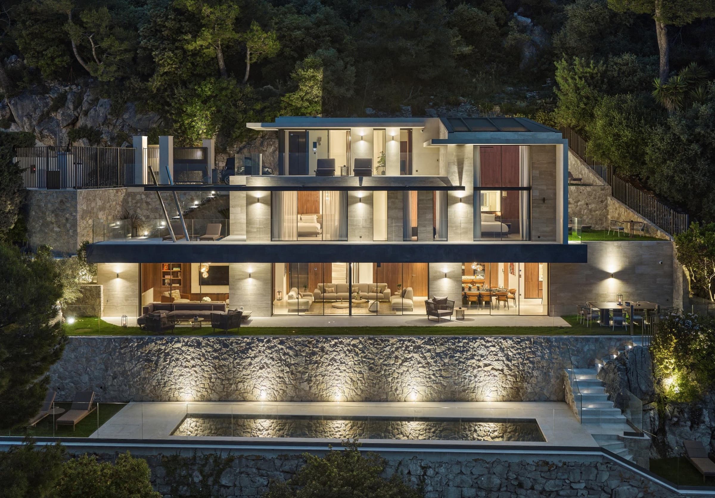 Villa Constance façade lit at nightfall, pool below